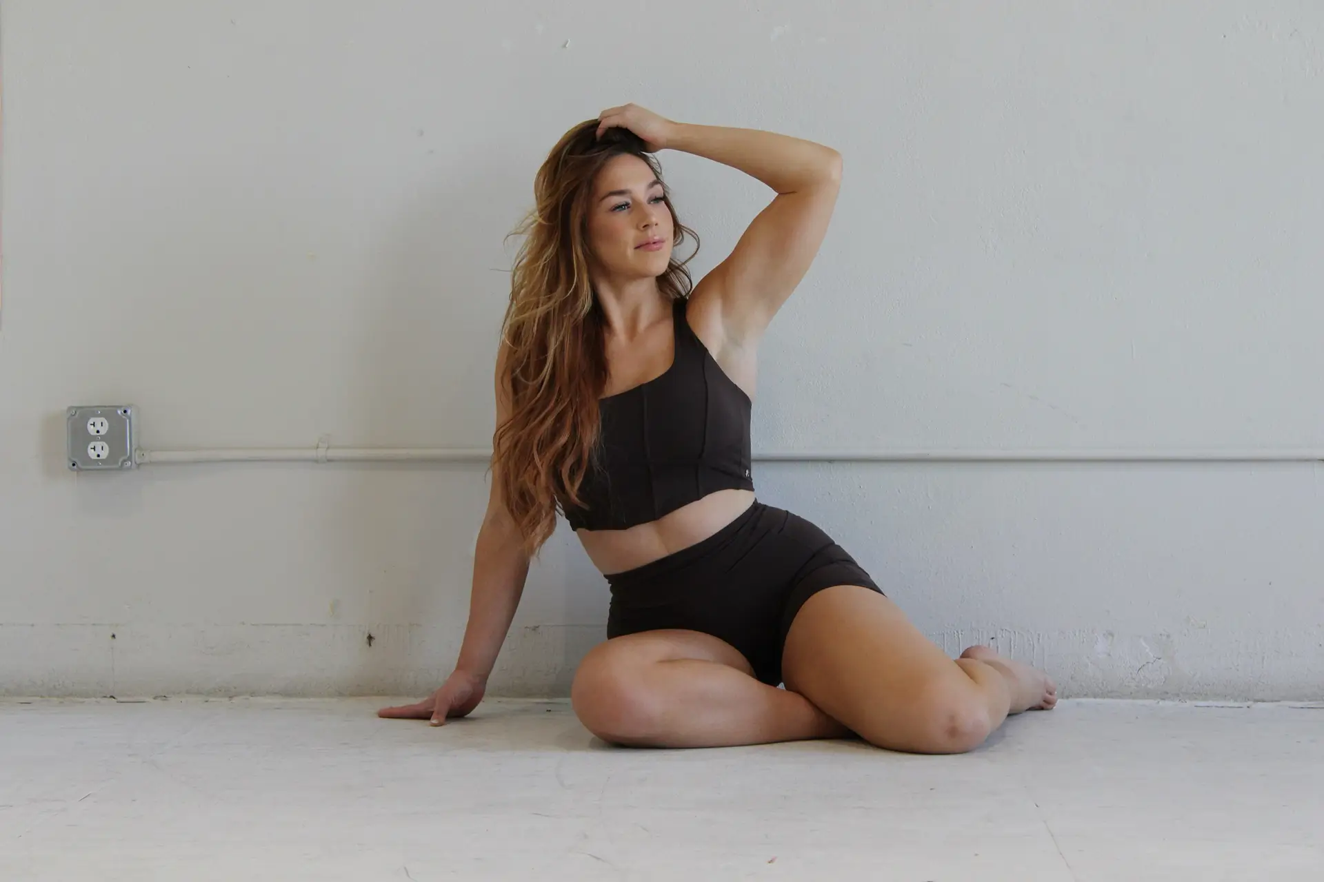 Image of a female fitness trainer sitting on the floor posing for yoga and pilates